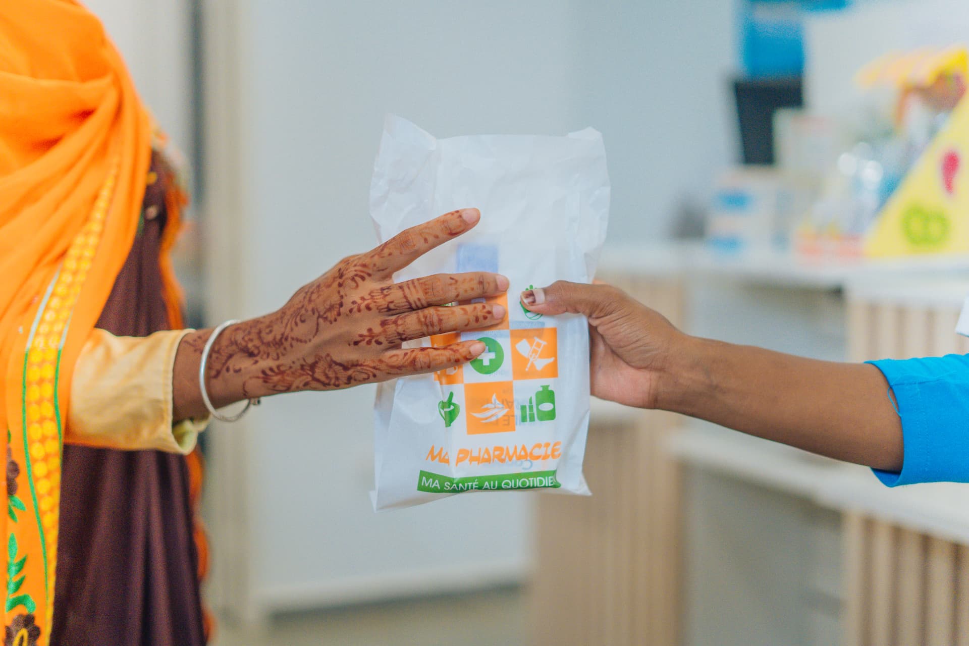 Remise d'un sachet à une patiente au comptoir de la pharmacie